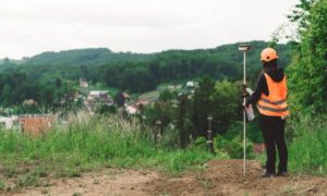 Land surveyor collecting elevation data near a residential property for an elevation certificate