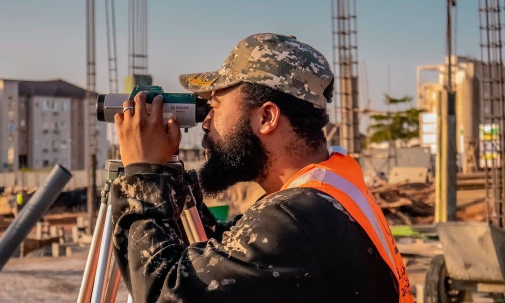 Surveyor using a surveying instrument at an active construction site for a construction survey